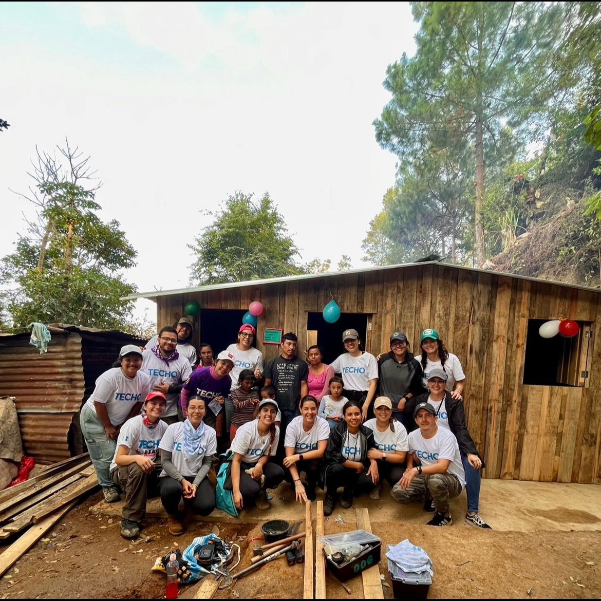 Inés with the TECHO team and a family in front of a newly built home in Guatemala